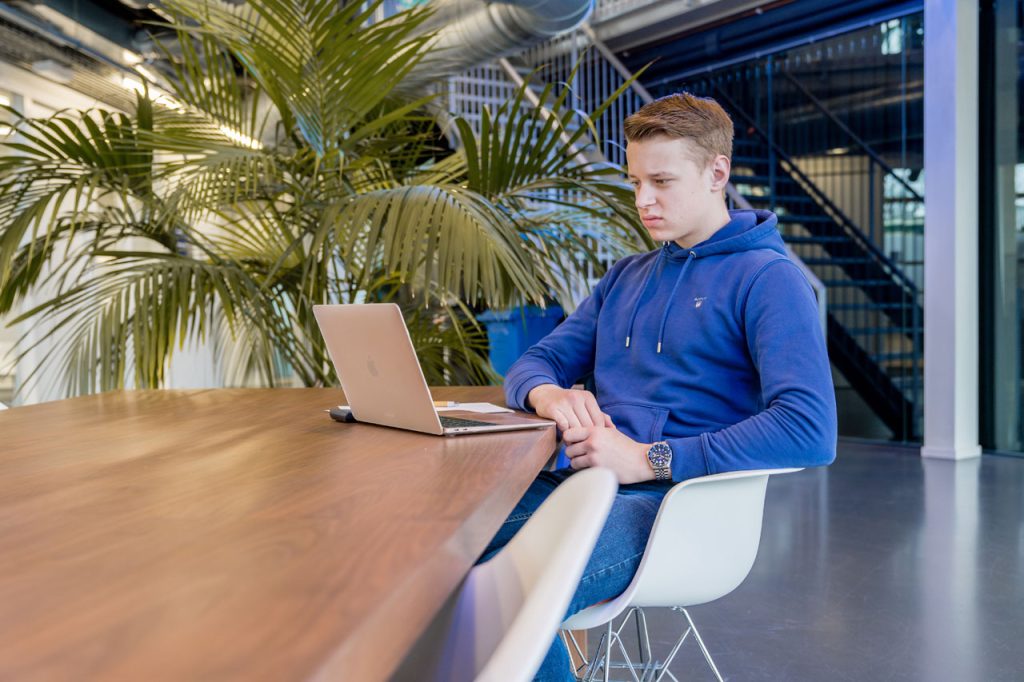 student in blauw shirt maakt op zijn laptop een oefensommen om rekenen te leren